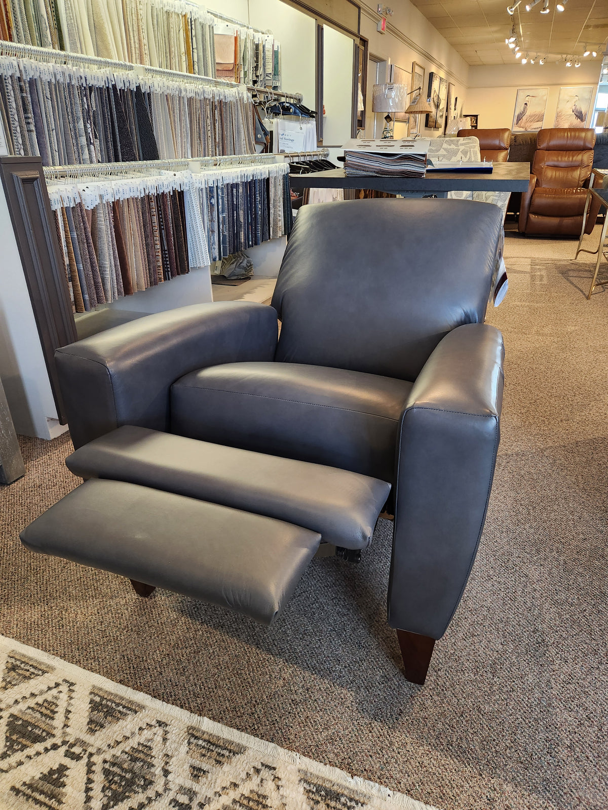 The La-Z-Boy 431 Scarlett dark gray leather high-leg recliner, made in the USA, is on display in the showroom.