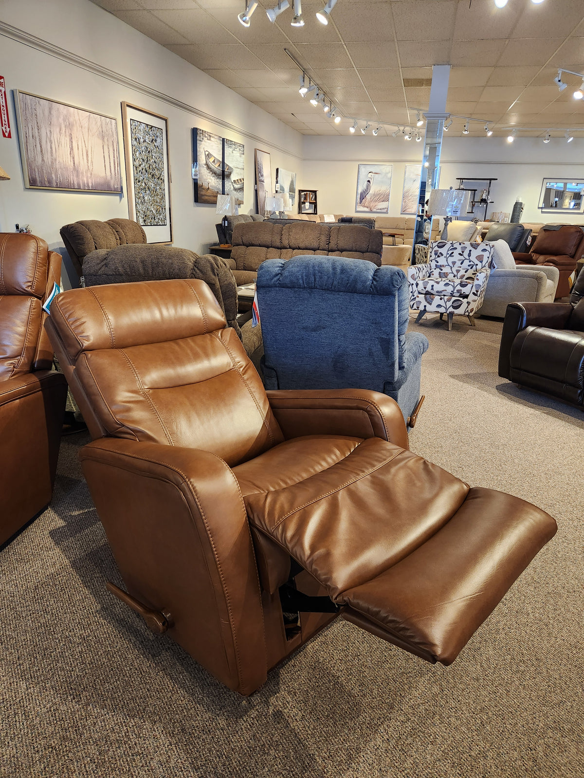 La-Z-Boy 807 Baron Rocker Recliner extended in a showroom with sofas, wall art, and lumbar support in the background.