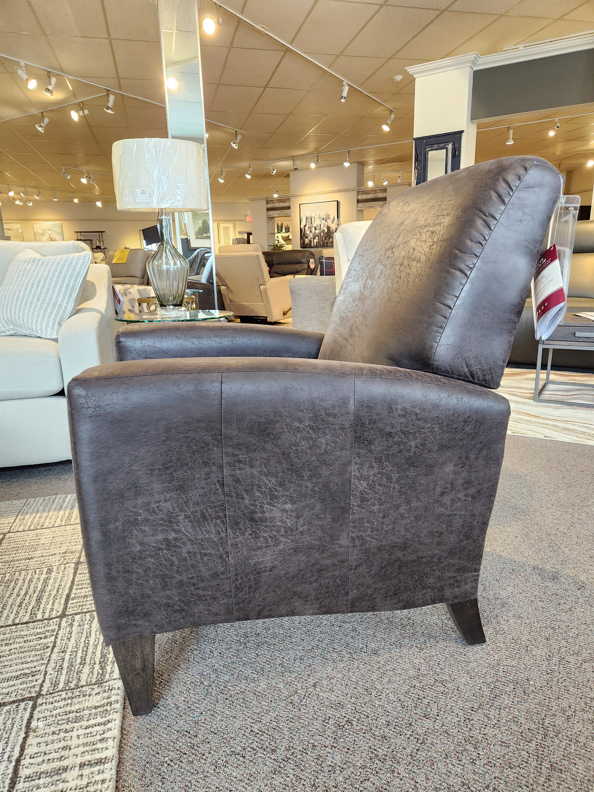 A dark brown La-z-boy 431 Scarlett High-Leg Recliner on display in a showroom, with other furniture in the background.