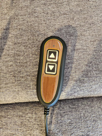 A wired remote for the Golden Aurora PL480 Power Lift Chair sits on textured brown fabric.