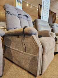 A Golden Aurora PL480 beige upholstered power lift chair with remote is on display in a furniture showroom.