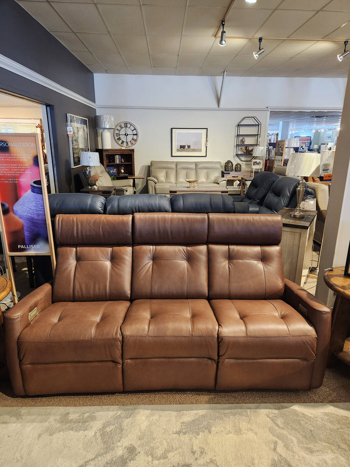 The Palliser 42204 West Coast power reclining sofa with headrest in brown leather, shown with home decor in the background.