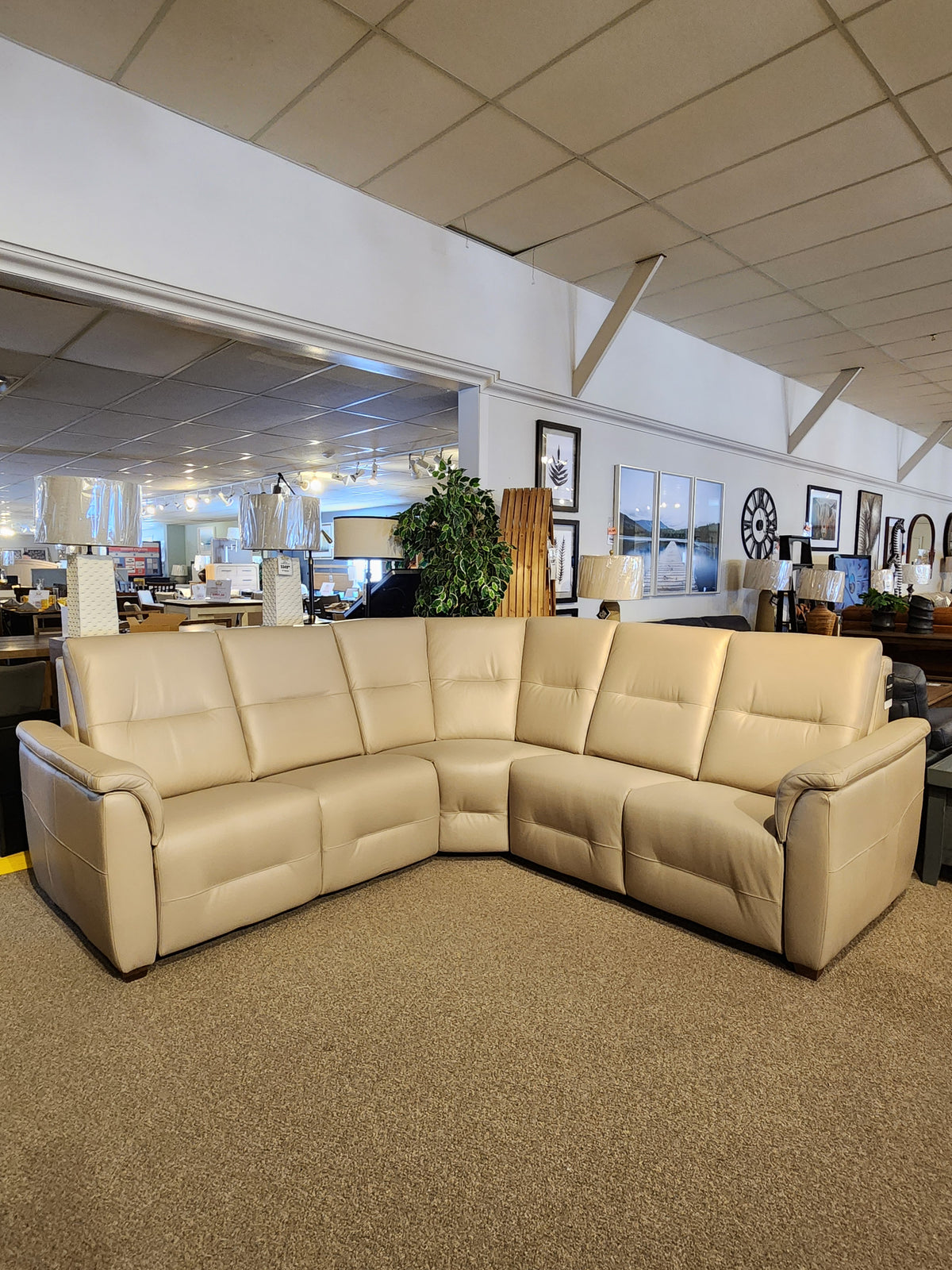 The Palliser Oxford 3-piece Sectional in beige leather with power recline is displayed amid decor and mirrors.