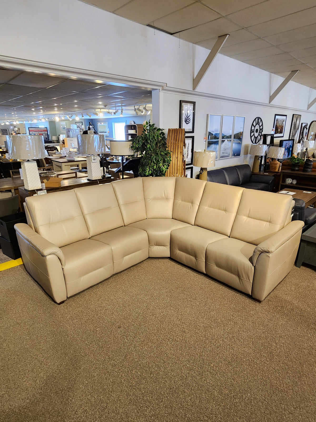The Palliser Oxford 3-piece Sectional, an L-shaped beige leather sofa with power recline and headrest, on display.