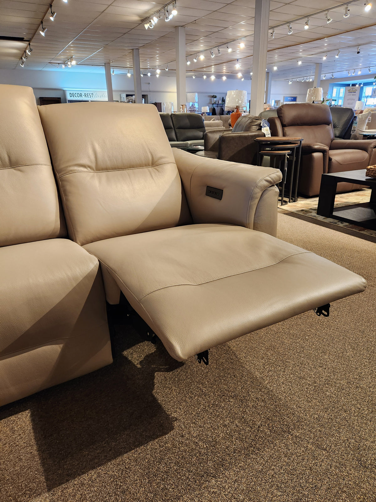 Palliser Oxford 3-piece Sectional in light beige leather with power recline and adjustable headrest on display.