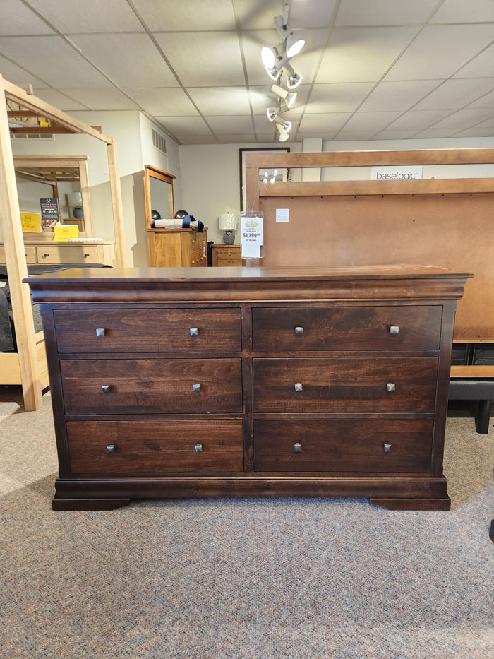 A traditional showroom displays the Vokes 260 Rustique 6 Drawer Dresser in dark wormy maple with matching pieces.