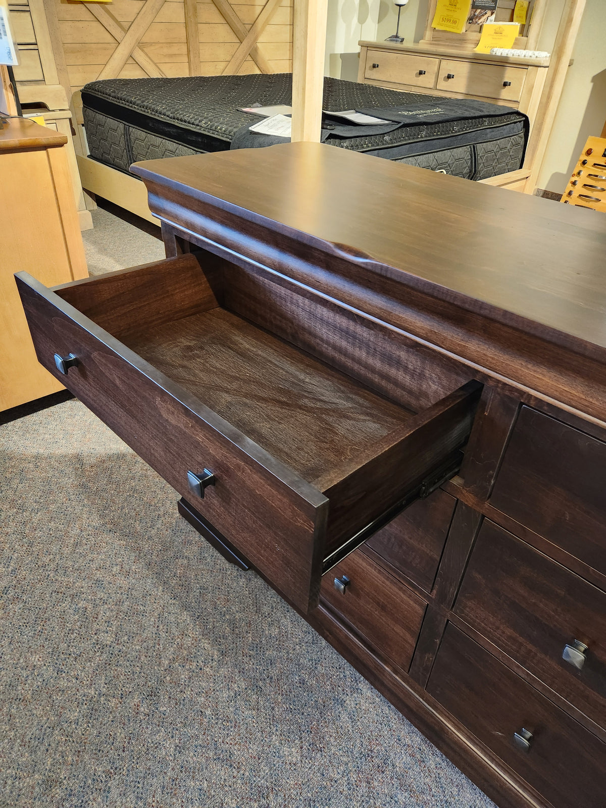 The Vokes 260 Louis Rustique 6 Drawer Dresser is displayed open amid traditional bedroom furniture in the showroom.