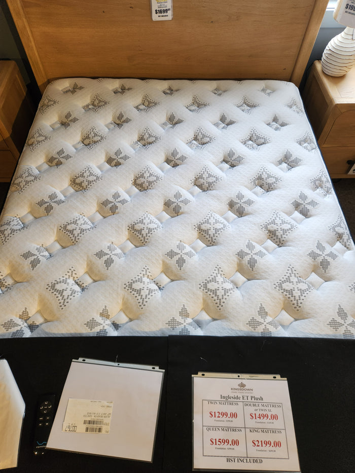 A KingsDown Ingleside ET Plush queen mattress on display with price tags and product details on a table in front.