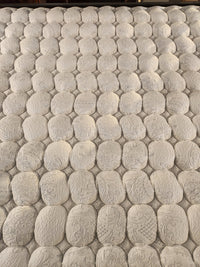 Close-up of KingsDown Mallory ET Firm Mattress surface with oval quilting, stitched detail, and cooling gel foam layers.
