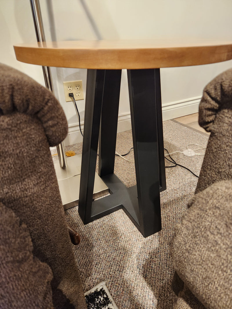 A Handstone Belmont Round End Table with a black metal base sits between two brown upholstered chairs.