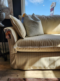 The Best Oxford Sofa, with a down-blend cushion, sits by a sunlit window in yellow and white stripes.