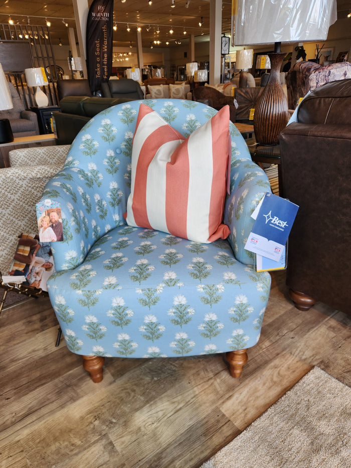 The Arden Club Chair by Best features blue floral button tufting and a red-white striped pillow on display.