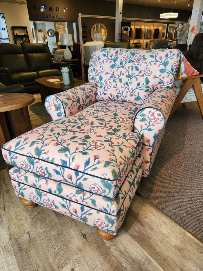 The Best Kress Chaise Lounge, featuring a floral pattern, exudes heirloom charm in the furniture showroom.