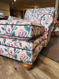 The Best Kress Chaise Lounge features heirloom charm and wooden legs, displayed on a wood floor in a showroom.