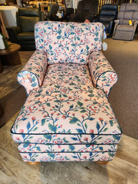 The Kress Chaise Lounge by Best features pink floral fabric, blue trim, and wooden legs for an heirloom-inspired charm.