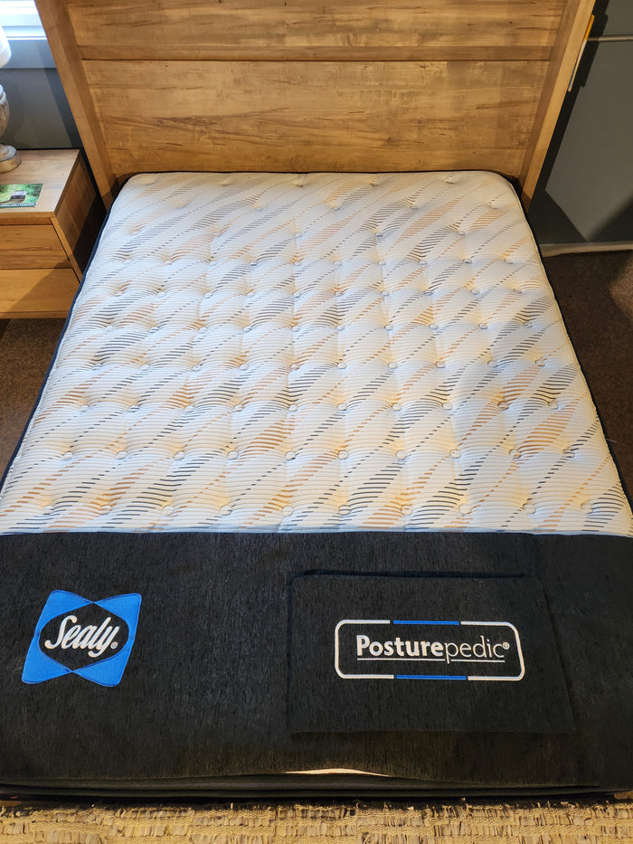 A Sealy Carmi ET 1000 Coil Copper Series mattress on a wooden bed frame, with brand logos visible below.
