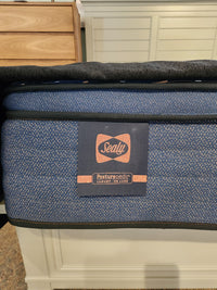 Close-up of a Sealy Rowan ET Medium 1300 Coil Copper Series mattress corner with logo tag on a blue, cooling surface.