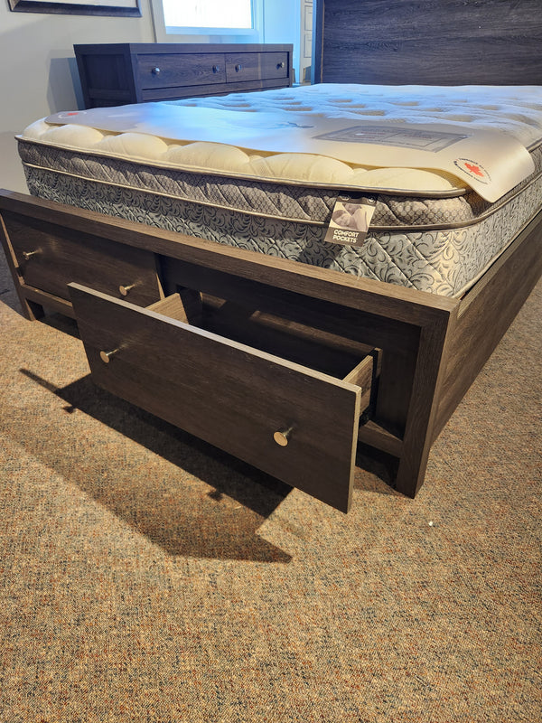 The Magnussen B6308 Merrifield Queen Storage Bed with oak veneer and drawers is set on a carpeted floor.