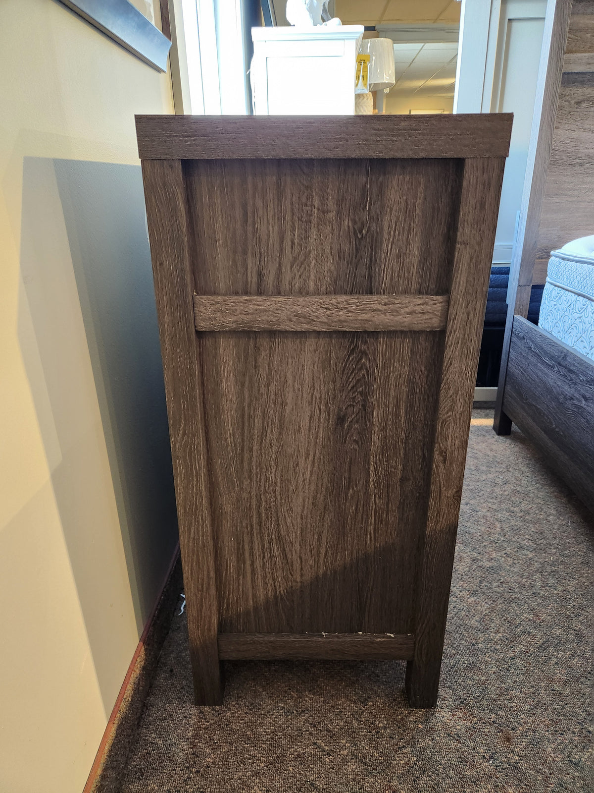The Magnussen B6308 - Merrifield Dresser with an oak veneer back panel stands on a carpeted floor in a modern bedroom.