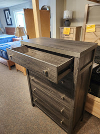 The Magnussen B6308 - Merrifield Chest, with a top drawer open, is displayed in the furniture showroom.