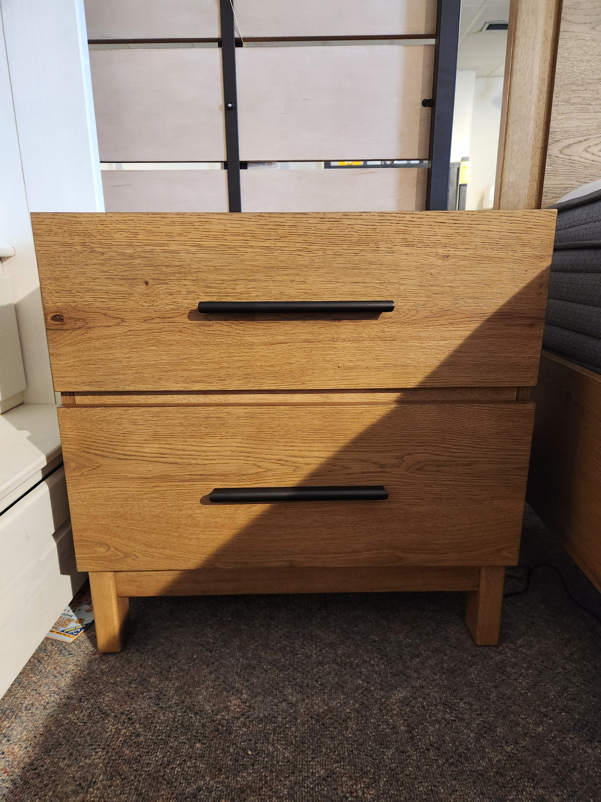 The Magnussen B6309 Davenport Nightstand in Rustic Caramel stands on a carpeted floor.