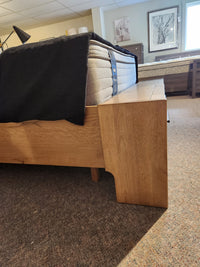 Magnussen B6309 Davenport Queen Storage Bed in Rustic Caramel with mattress, black blanket, and artwork showroom.