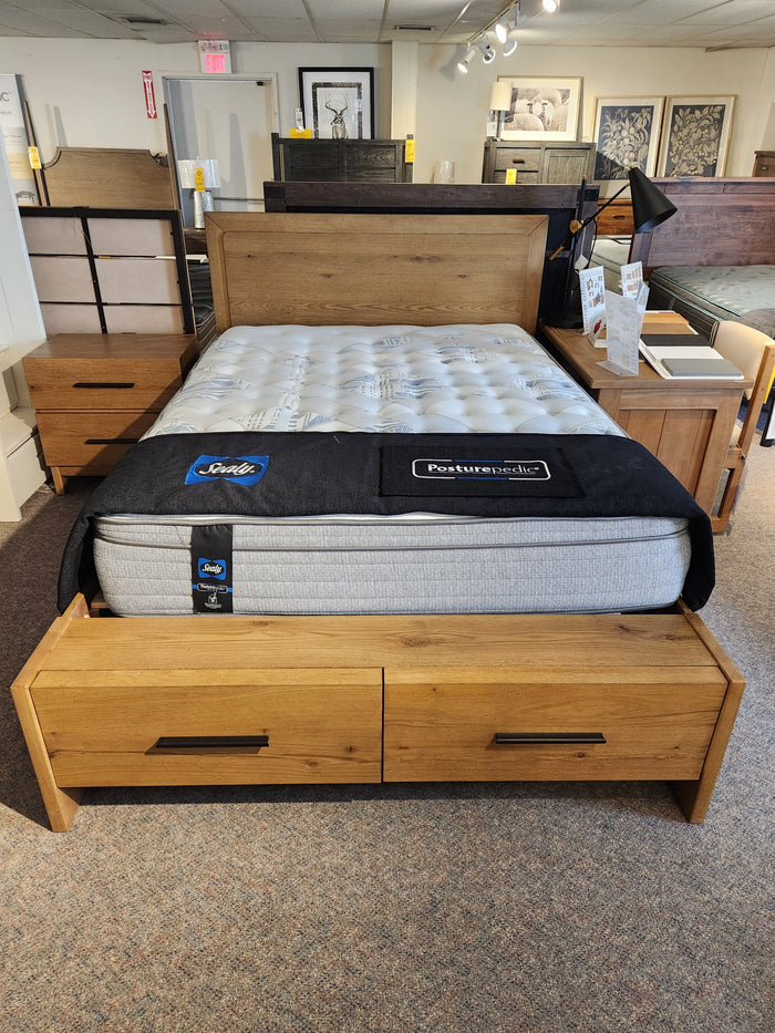 The Magnussen B6309 Davenport Queen Storage Bed in Rustic Caramel with storage drawers is displayed in a showroom.