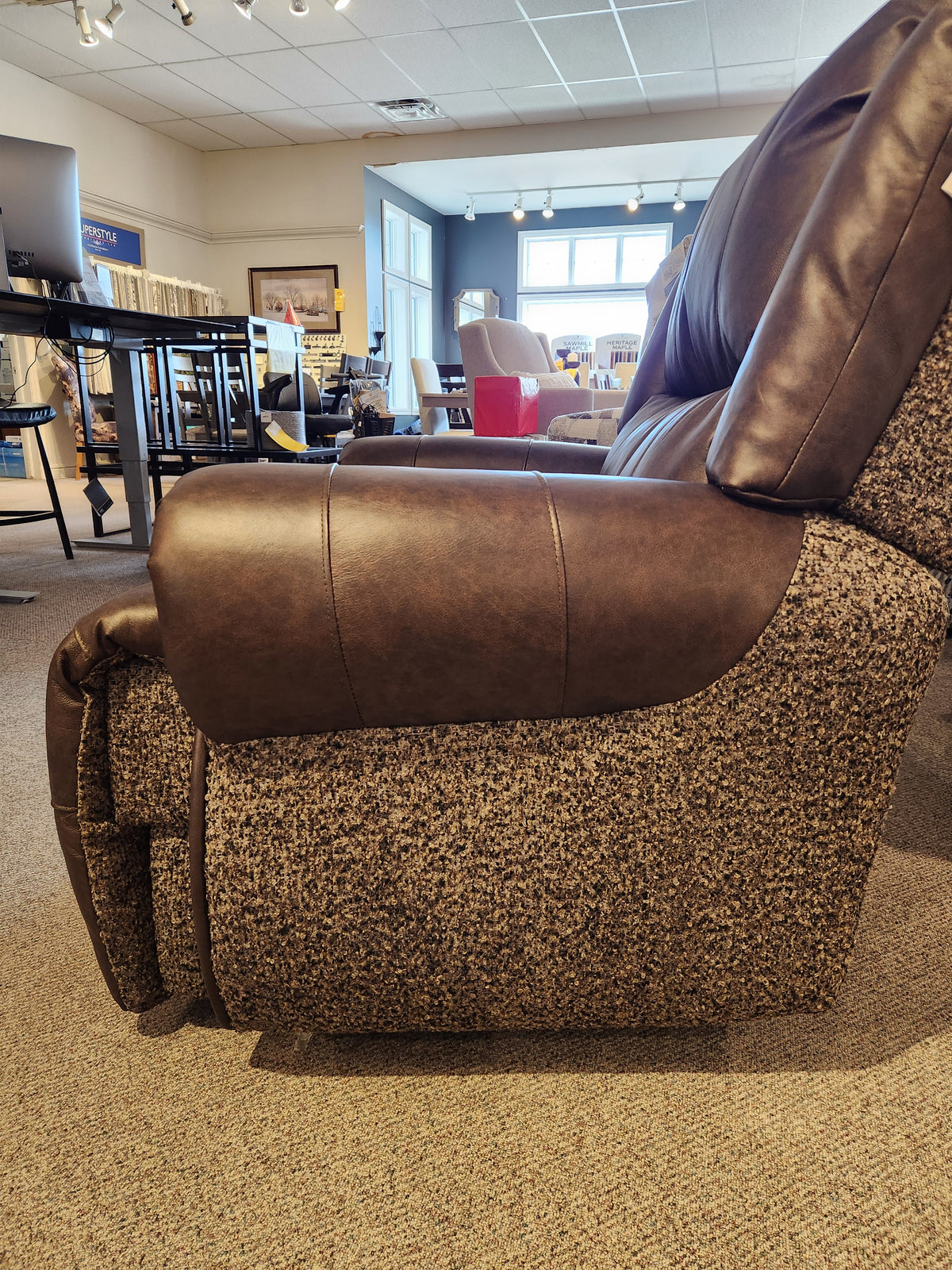 FS9N64LF Garnet Reclining Chair by Best in brown and gray on carpeted showroom floor with tables and chairs behind.