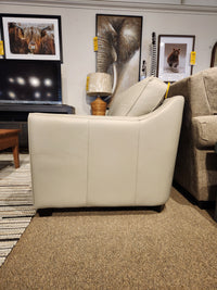 Side view of a Leather Craft Sophia Loveseat in light gray Canadian leather, with animal art and a lamp in the background.