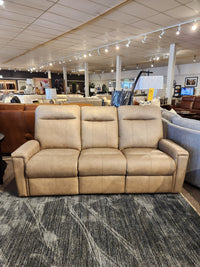 The Decor-rest M8520 Power Reclining Sofa in tan leather is shown on a dark textured rug in the showroom.