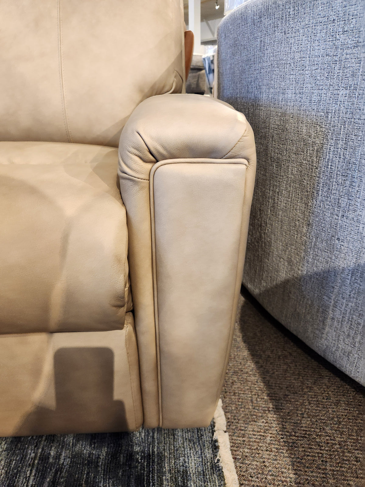 Close-up of Decor-rest M8520 Power Reclining Sofa armrest in beige leather beside a gray fabric chair on carpet.