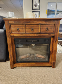 Jofran 1900 Bakersfield 32" Fireplace with three drawers and adjustable flame, displayed with framed art in showroom.