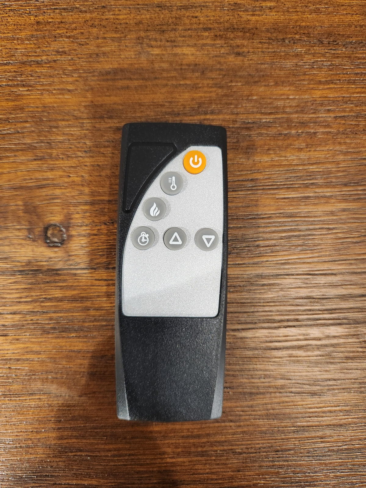 A Jofran 1900 Bakersfield 32" Fireplace remote with six flame controls rests on a wooden surface.