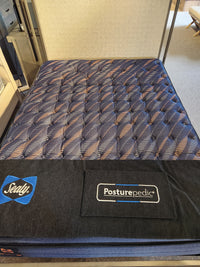 A Sealy Roux ET Soft 1300 Coil Copper Series mattress with a blue and black top displayed in a showroom.