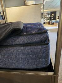 A close-up side view of the Sealy Roux ET Soft 1300 Coil Copper Series mattress on display in a showroom.