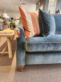 Best Adeline Sofa in blue velvet with reversible cushions and striped pillow, beside a wooden table with decor.