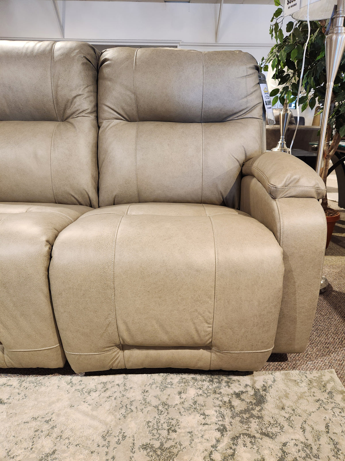 The Best Maverly S910 Space Saver Recliner Sofa in beige with plush cushions and Tilt Headrest is shown in a showroom.