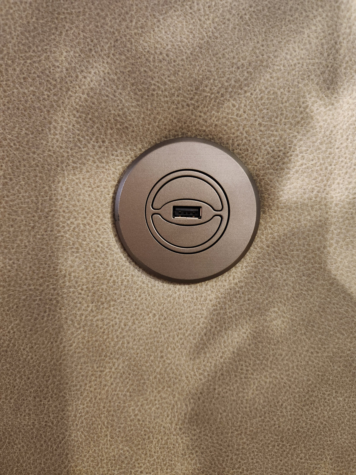 A round USB port is built into the textured tan Maverly S910 Space Saver Recliner Sofa by Best.