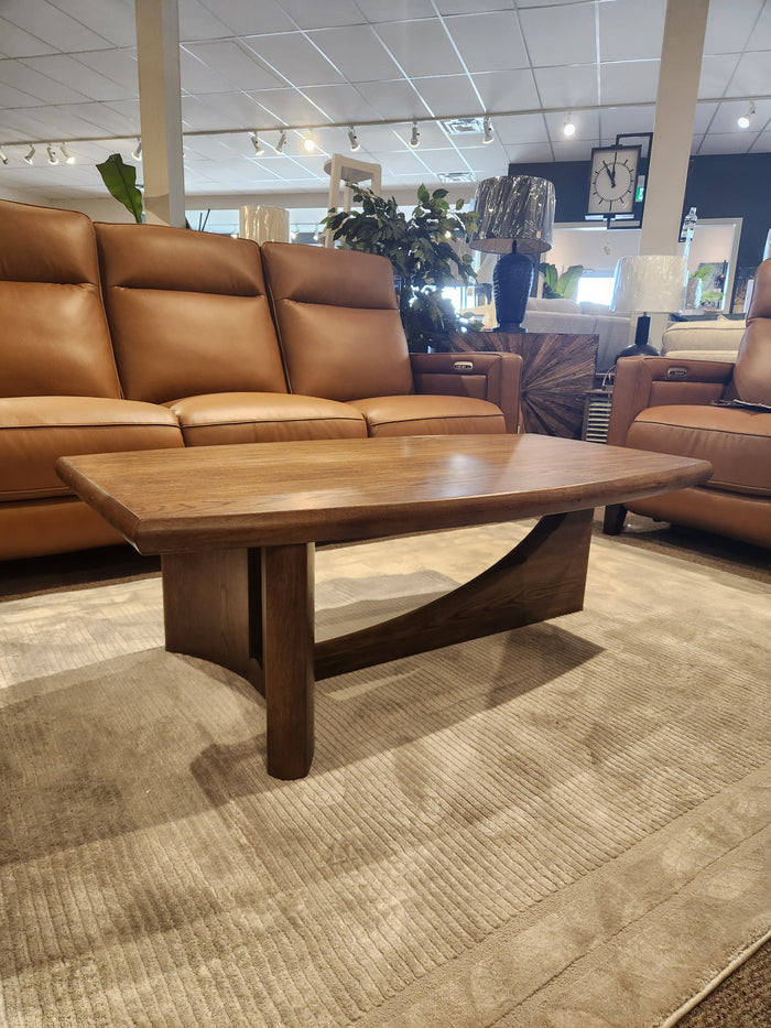 The Magnussen T6385 Phoebe Rectangular Cocktail Table rests on a rug between two tan leather sofas in a modern living room.