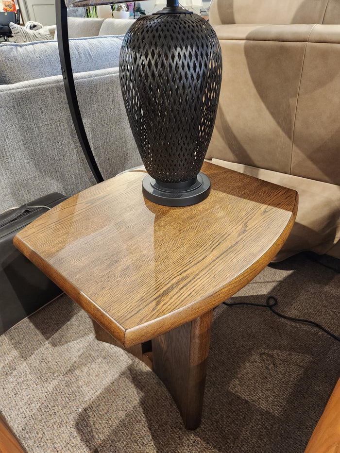 A Magnussen Phoebe T6385 end table in Sienna Brown with a black lamp, beside a beige sofa on carpet.