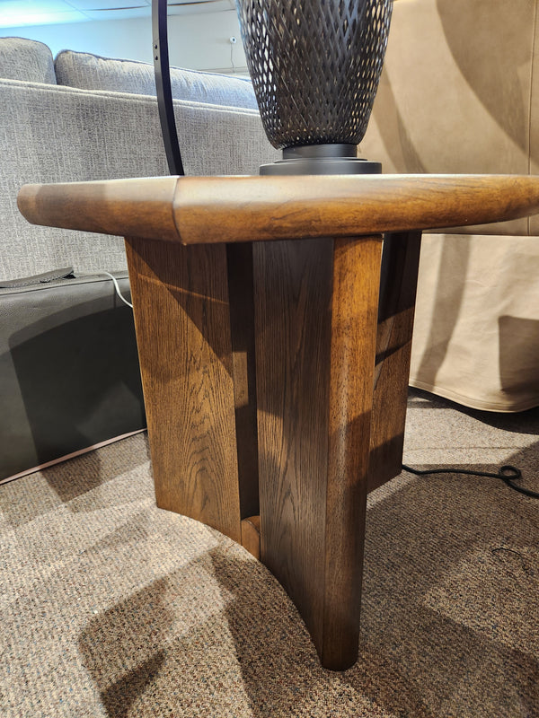 Magnussen T6385 - Phoebe Rectangular End Table in Sienna Brown oak veneer with paneled legs, shown beside a sofa.