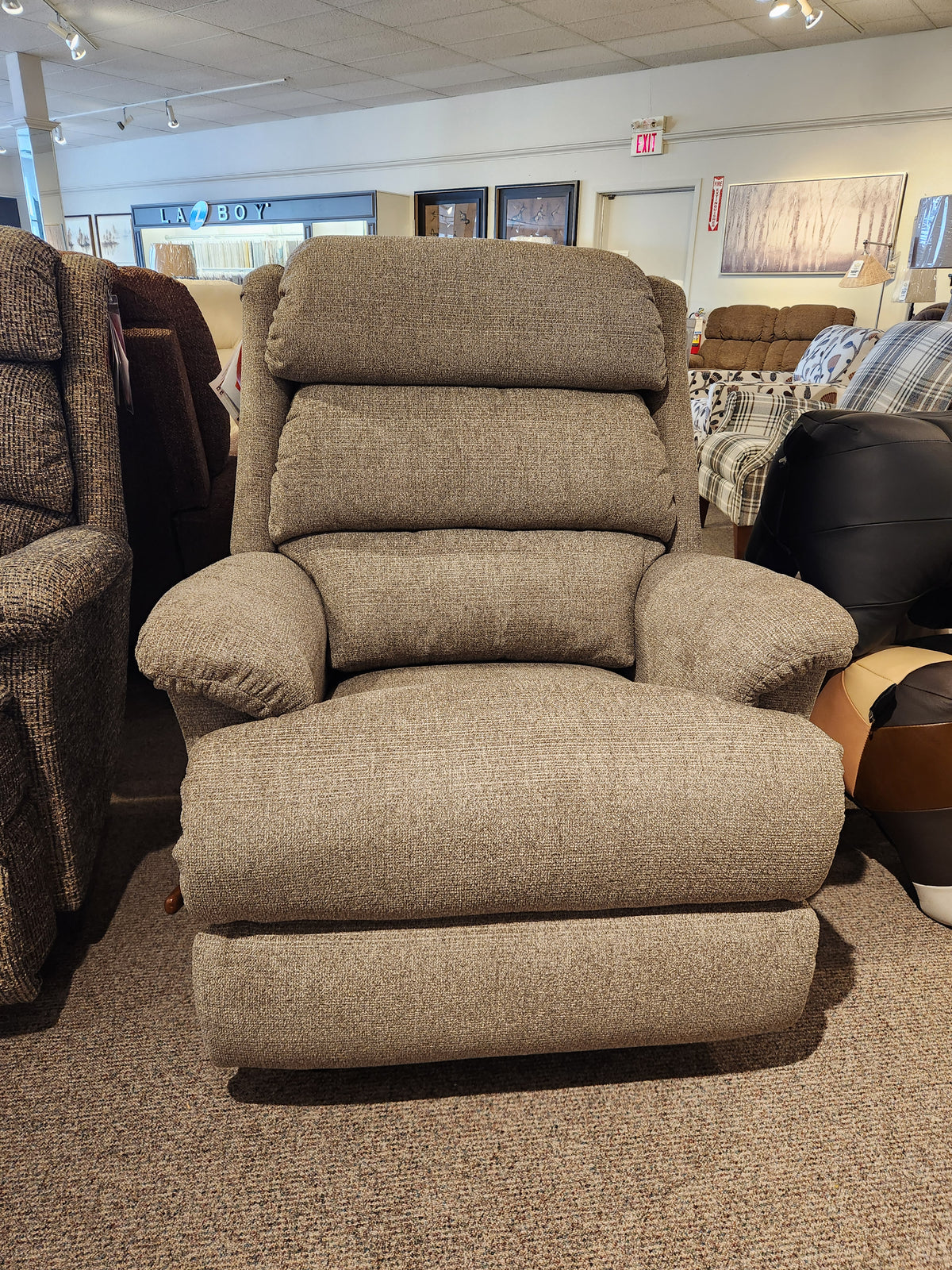 The La-z-boy 519 Astor Rocker Recliner has an adjustable cushioned back, displayed with other chairs in the showroom.