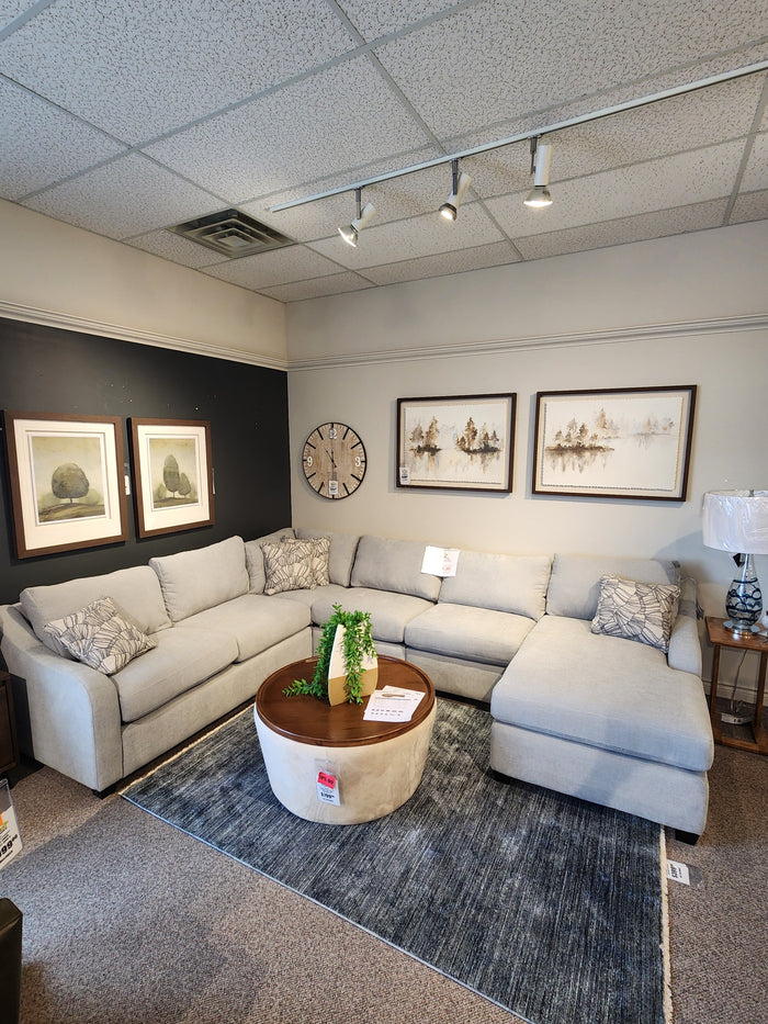 Light gray La-Z-Boy Charlie-638 Sectional with throw pillows, dark rug, round ottoman, wall art, and clock.