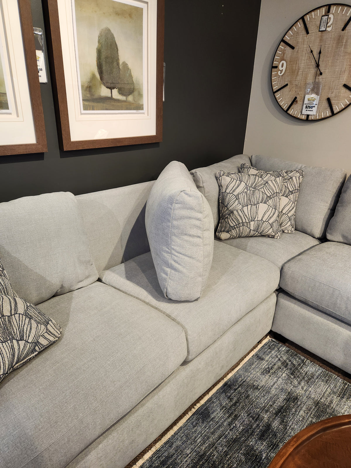 Light gray La-Z-Boy Charlie-638 Sectional with patterned pillows, wall clock, and tree art on a dark wall.