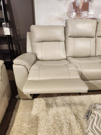 The 16 WEST Austin Power Recliner Sofa-520157 with extended footrest is on a cream shag rug near modern art.