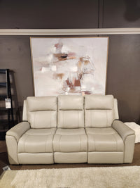 The 16 WEST Austin Power Recliner Sofa-520157 sits by an abstract painting, dark wall, and a light rug beneath.
