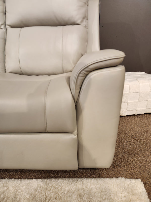 Close-up of the 16 WEST Austin Power Recliner Sofa-520157 in light gray leather beside a white ottoman and rug.