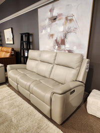 16 WEST Austin Power Recliner Sofa-520157: Beige leather, 3 seats, displayed in showroom with brown wall and abstract art.