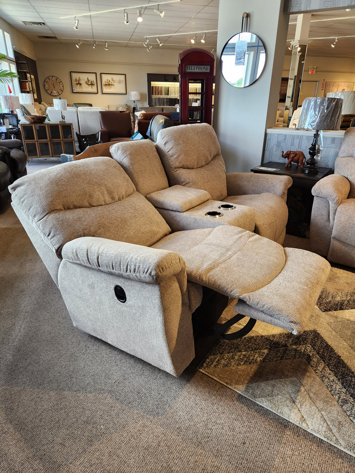 Two beige 521 James Loveseat with console by La-z-boy are in the showroom alongside other seating and decor.