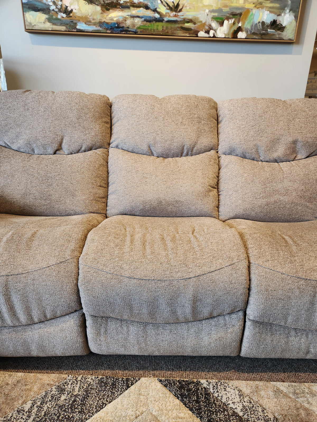 A tan La-z-boy 521 James sofa with three cushions rests on a patterned rug beneath artwork.